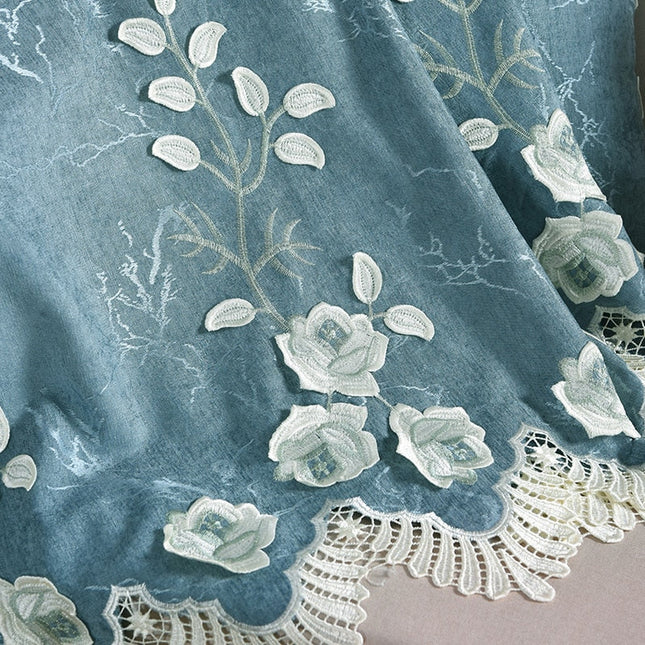 Niebieska zasłona z białym haftem kwiatowym